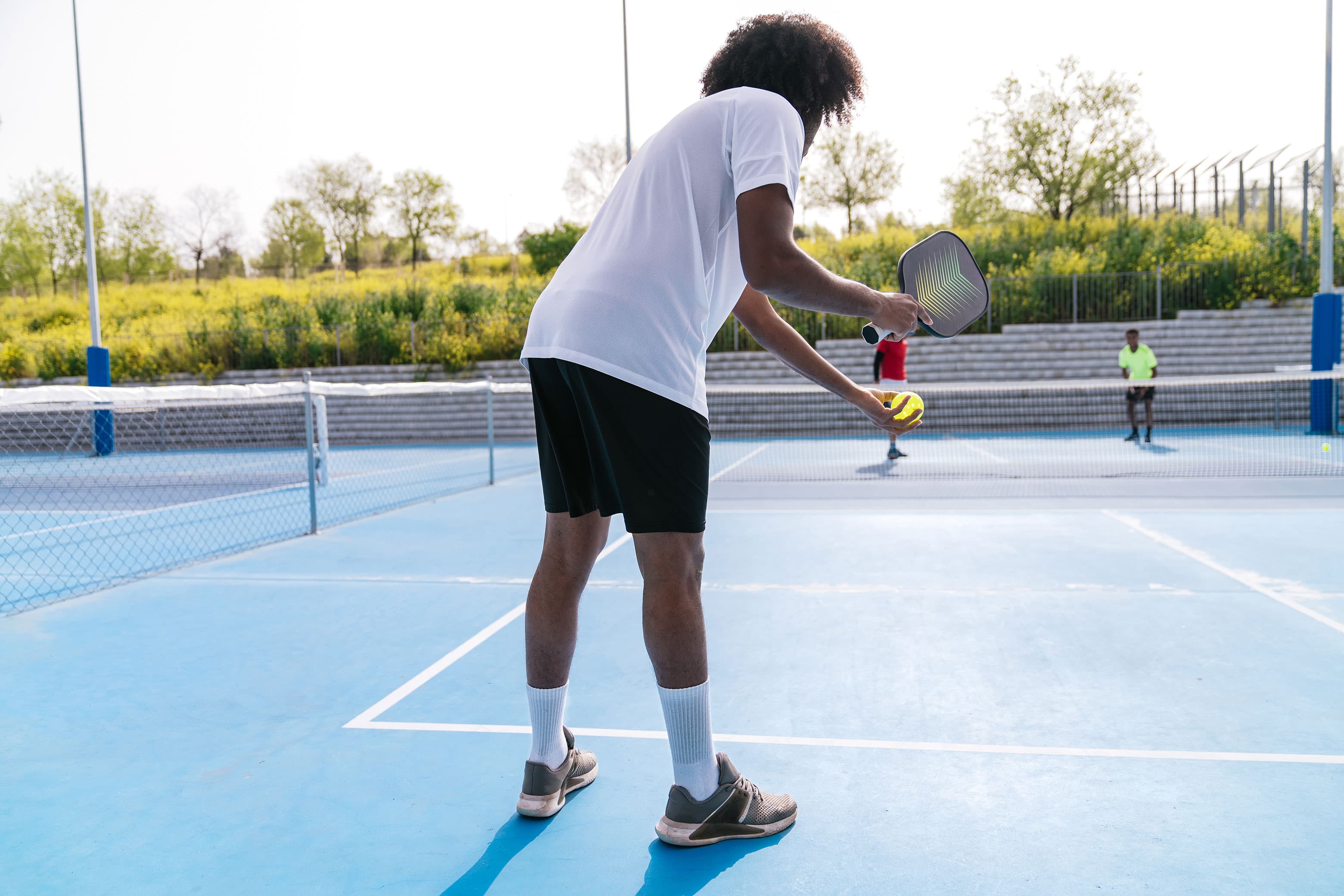 Four players in position during a doubles point on an outdoor court