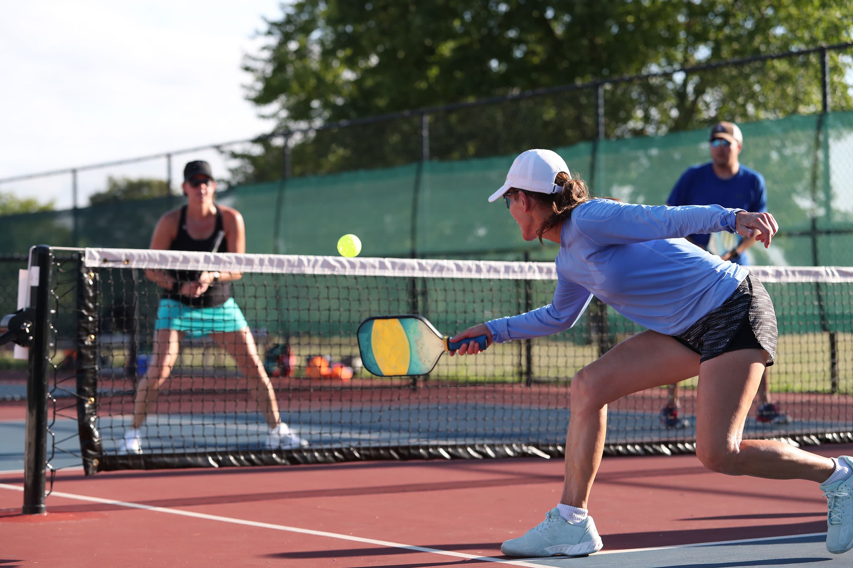 Players mid-rally at the net during an outdoor doubles game